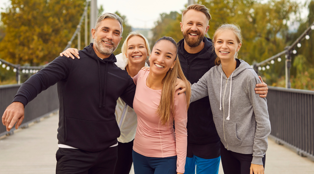 Gruppe strahlender Menschen, die nach dem Sport ihre Erfolge feiern und sich gemeinsam über ihre Gesundheit freuen.